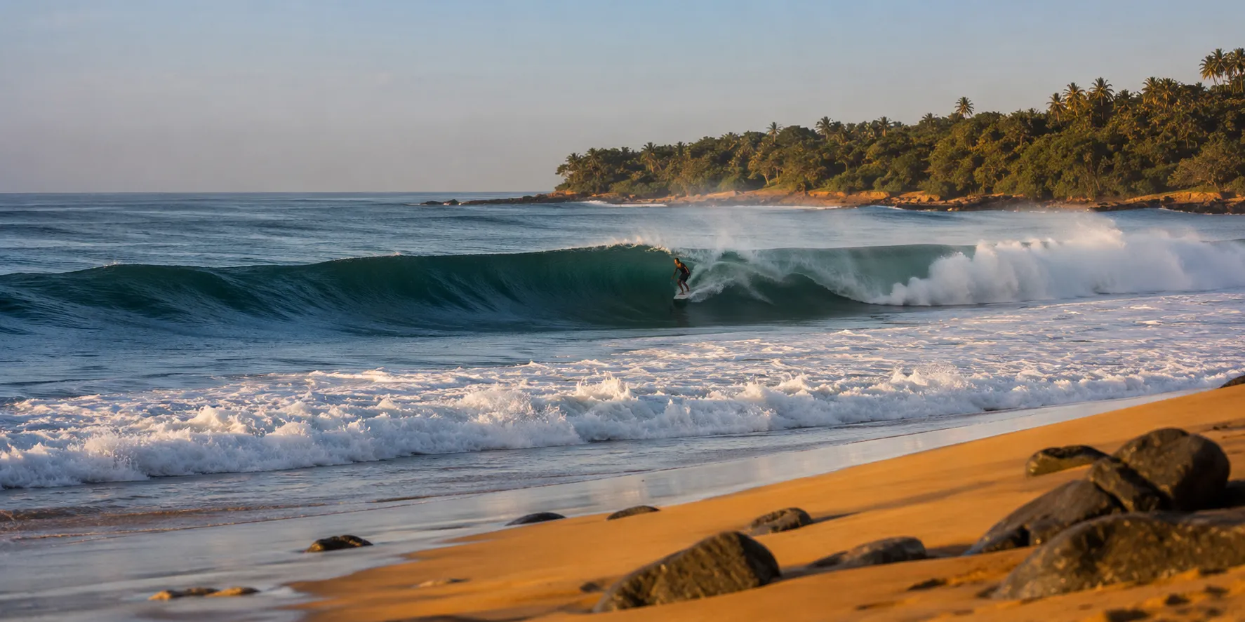 A long right-hand point wave peeling at Arugam Bay with a surfer riding it.