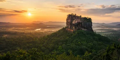 Sigiriya rock fortress rising above the forest at sunrise in Sri Lanka.