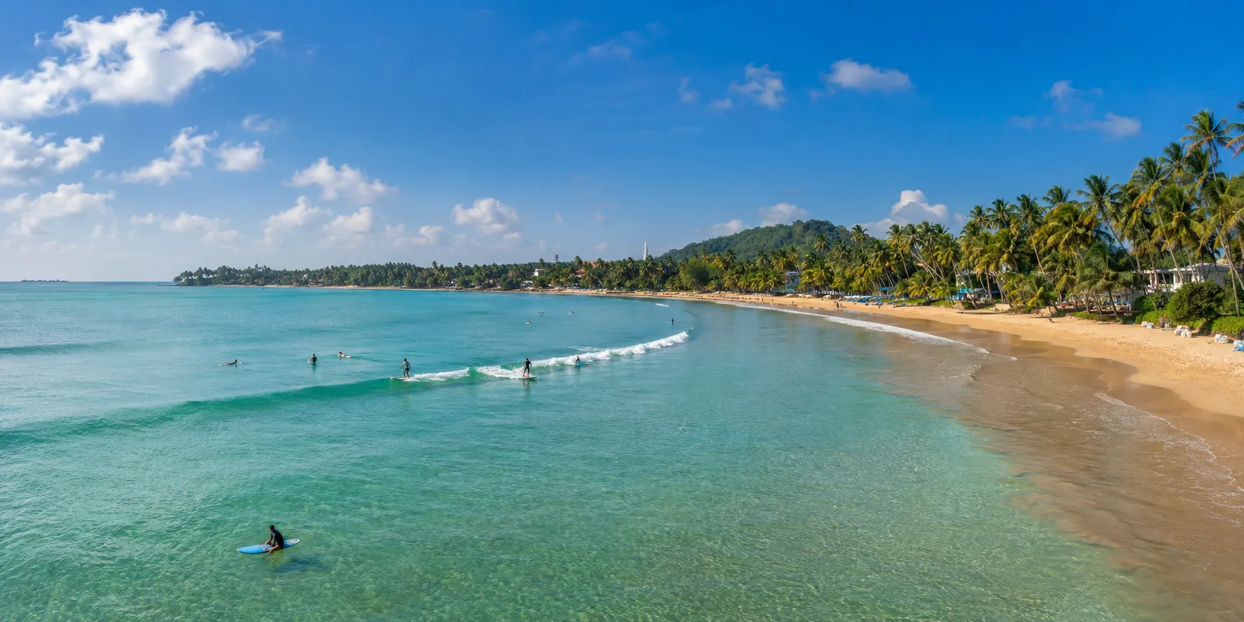 Beginner surfers on small waves at Weligama Bay.